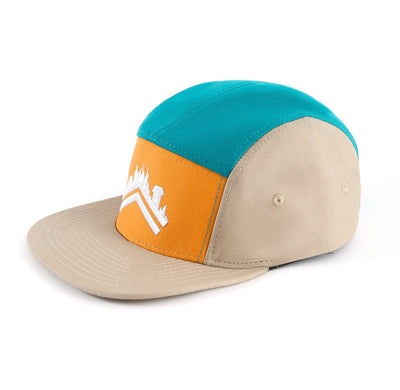 A side profile detail shot of the Friluft teal orange tan 5 panel cotton camper hat with a white aldri sur logo embroidered on the front panel 